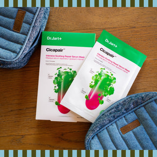A box and single packet of a K-beauty face mask displayed on a wooden surface between two blue quilted denim bags, with a green and blue striped border framing the image.
