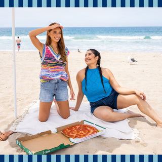 Two women smiling while wearing Judy Blue at the beach. The photo is being used to promote new styles for summer.